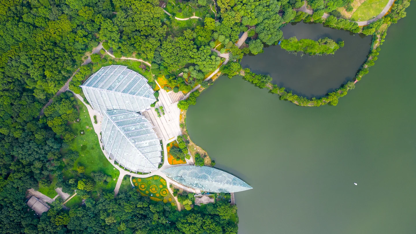A white waterfront building sits beside green parkland and a lake, viewed from above.